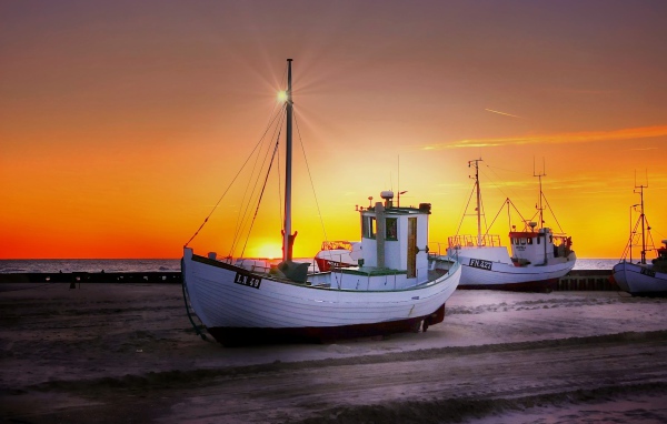 Рыбацкая лодка на берегу на закате 