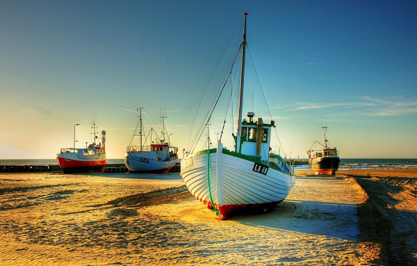 Рыболовные лодки в лучах солнца на берегу 