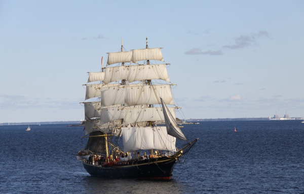 Большой черный корабль с белыми парусами в море