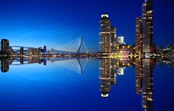 Небоскребы и мост отражаются в тихой воде