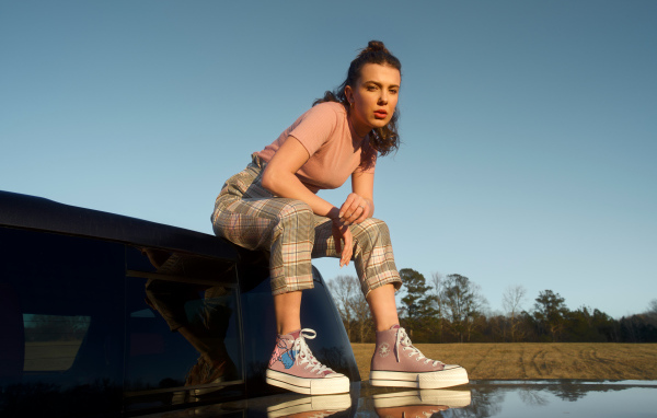 Актриса Милли Бобби Браун сидит на машине в кедах