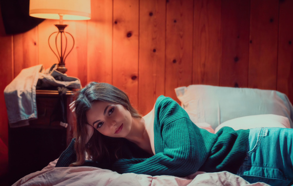 Актриса  Виктория Джастис в зеленом свитере на кровати