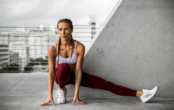 Спортивная девушка делает растяжку у стены 