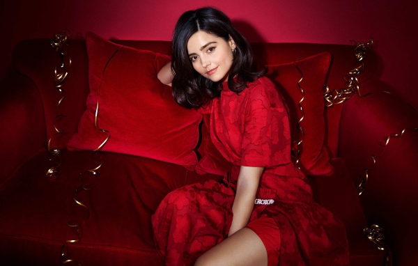 Красивая британская актриса Дженна Коулман сидит на красном диване