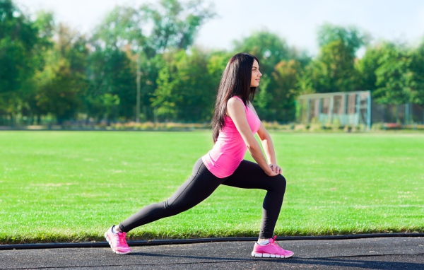 Девушка делает растяжку на поле 