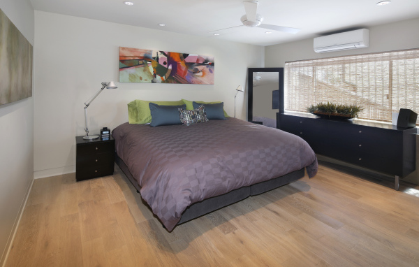 Большая серая кровать в спальне с белыми стенами