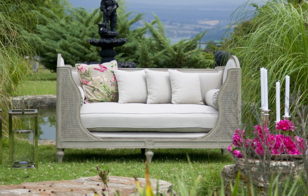 Большой серый диван в саду у пруда 