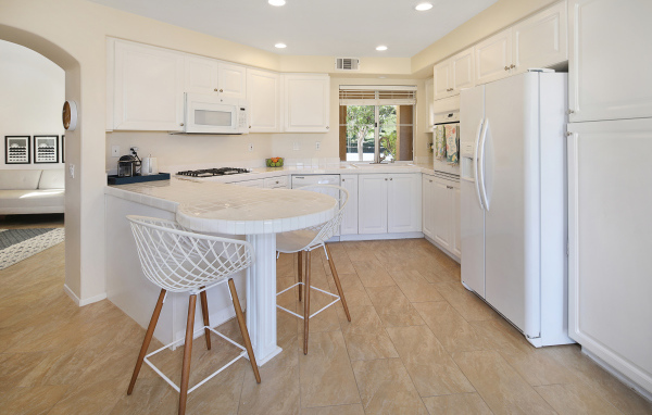 Большой холодильник и белая мебель на кухне 