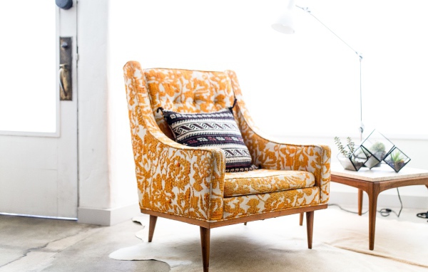 Старое кресло с подушкой в комнате 