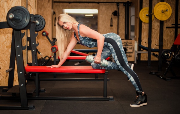 Стройная спортивная девушка с гантелей