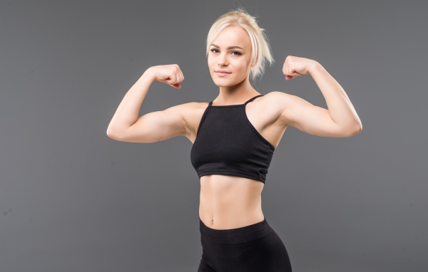 Спортивная блондинка в черном костюме на сером фоне