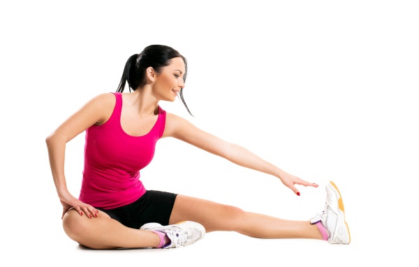 Спортивная девушка делает растяжку на белом фоне 