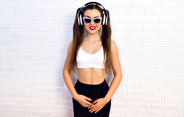 Спортивная девушка в очках у стены