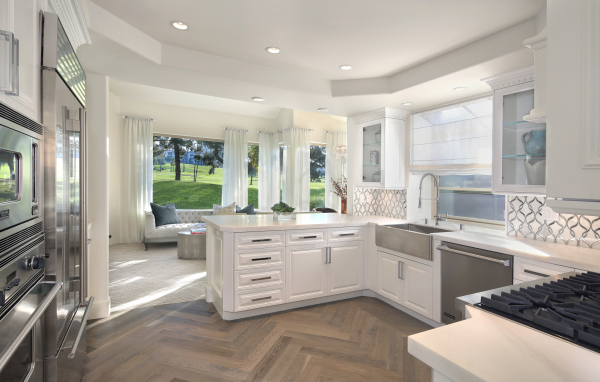 Белый кухонный гарнитур в комнате с большим окном