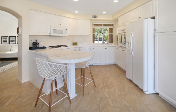 Белая стильная мебель с большим холодильником на кухне