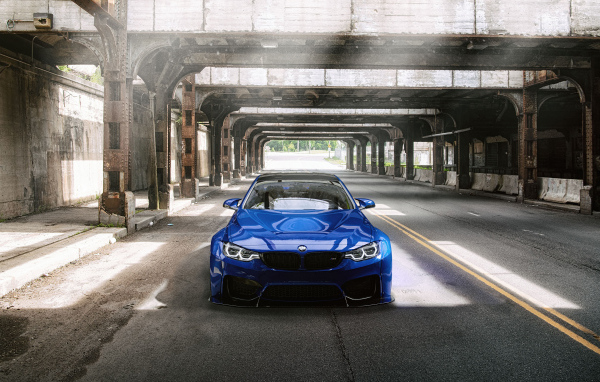 Синий автомобиль BMW M4 под мостом