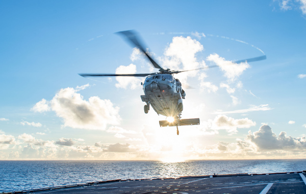 Military helicopter lands on a ship at sea