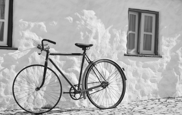 Черный велосипед стоит у белой стены