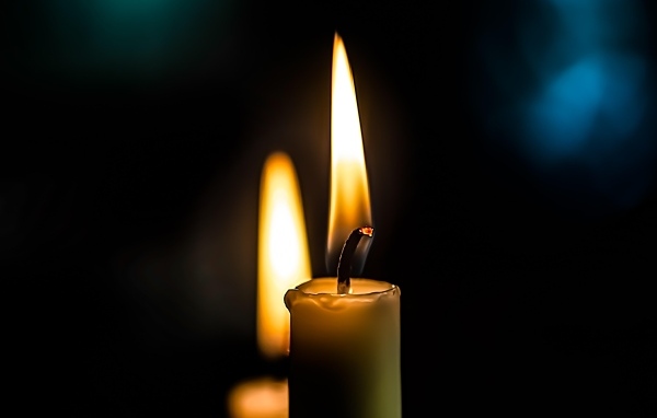 Зажженная свеча на черном фоне