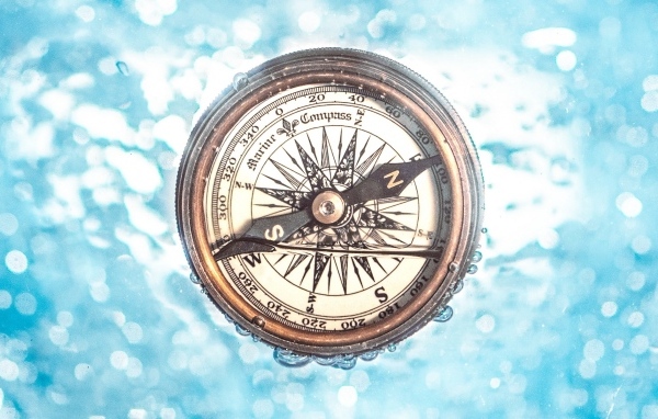 Старый компас в воде на голубом фоне