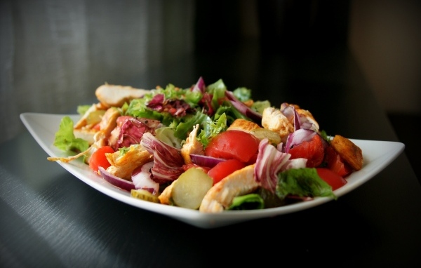 Аппетитный салат в белой тарелке на черном фоне