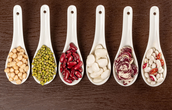 Бобовые зерна в белых ложках на столе