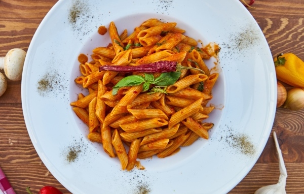 Вареные макароны на большой тарелке с красным перцем