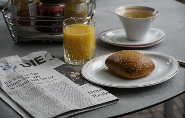 Булочка и стакан сока на столе с газетой