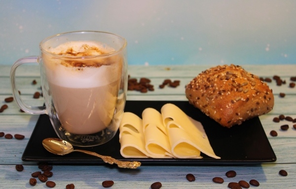 Сыр на тарелке с какао и булочкой