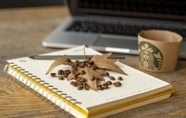 Зерна кофе с листом и блокнотом на столе