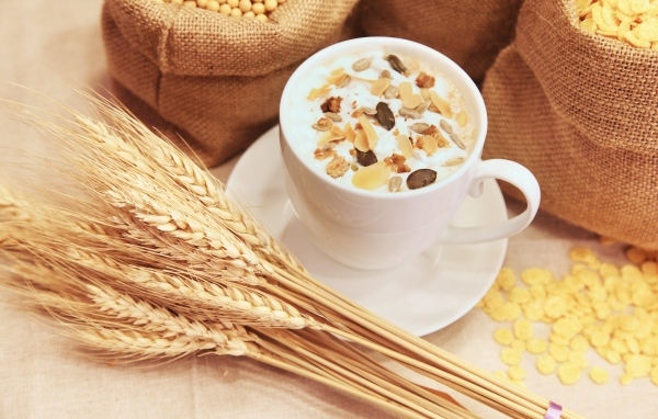 Чашка молока с хлопьями на столе с пшеницей