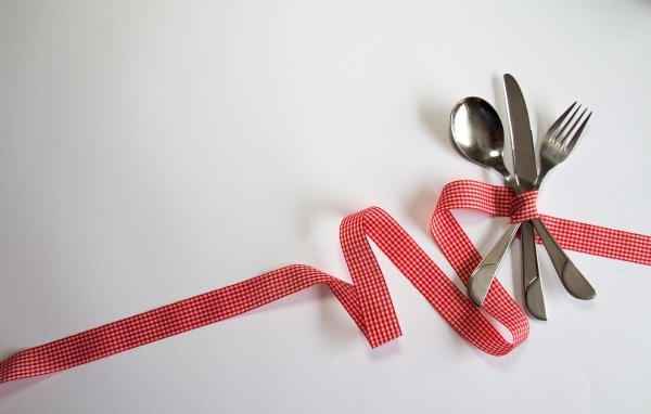 Столовые приборы перевязаны лентой на сером фоне
