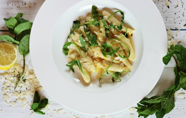 Блюдо с листьями рукколы в большой белой тарелке