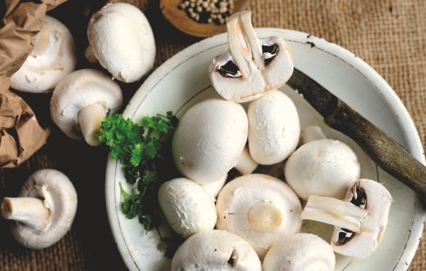 Свежие шампиньоны на тарелке на столе