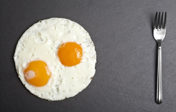 Яичница глазунья с вилкой на сером столе