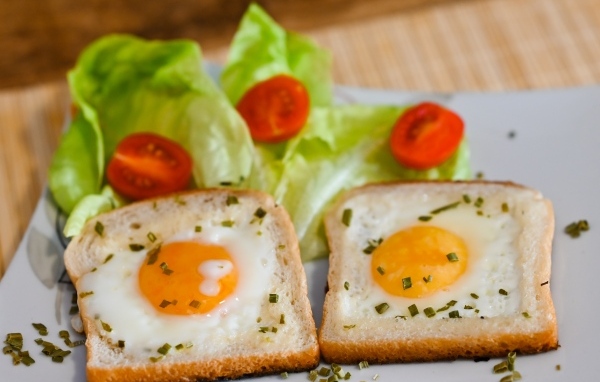 Яичница с хлебом, помидорами и листьями салата на завтрак