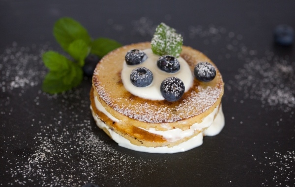 Оладьи с кремом и ягодами черники на столе