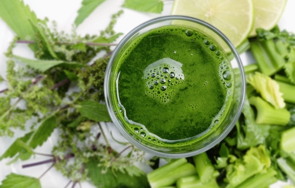 Зеленый овощной смузи в стакане на столе