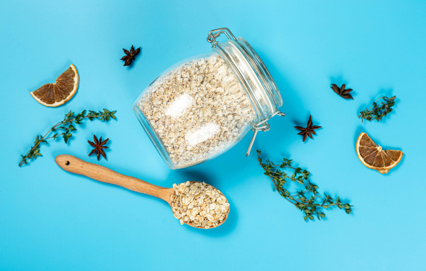 Банка с овсяными хлопьями и ложкой на голубом фоне