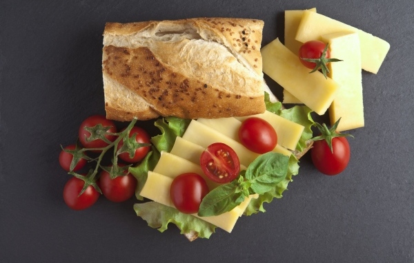 Батон с сыром и помидорами на сером фоне