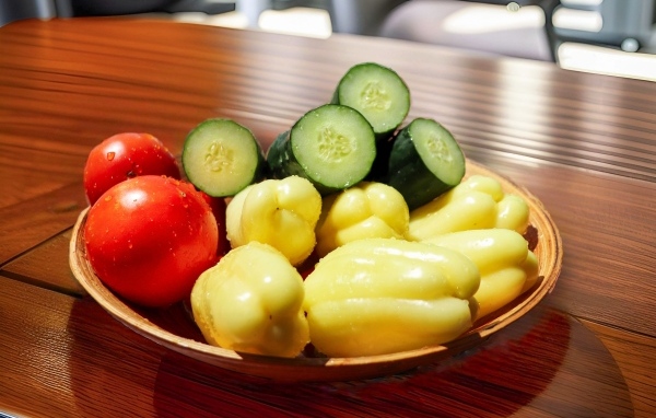 Перец, помидоры и зеленые огурцы на тарелке на столе