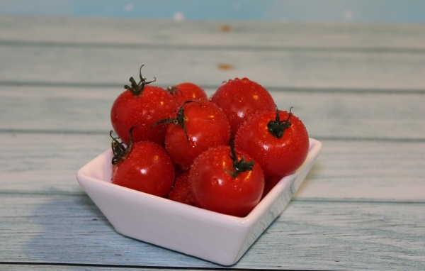 Красные мокрые помидоры в белой тарелке