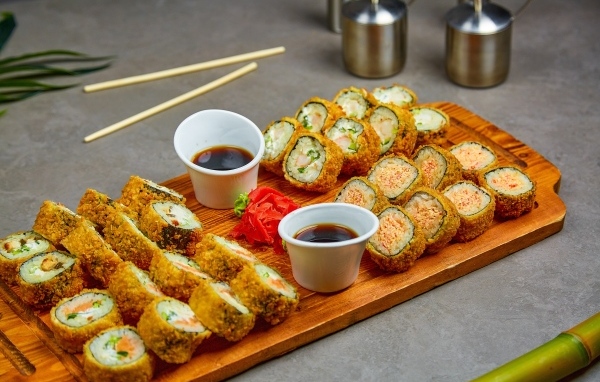 Роллы с соевым соусом на доске на столе