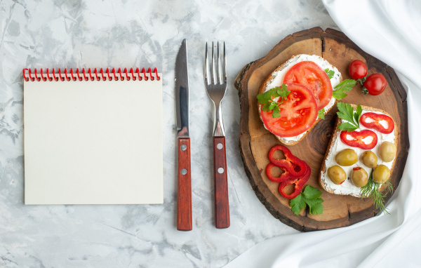 Бутерброды на столе со столовыми приборами и блокнотом