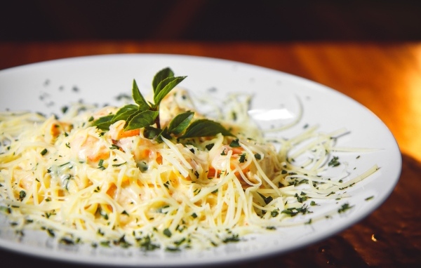 Спагетти с сыром и помидорами на белой тарелке