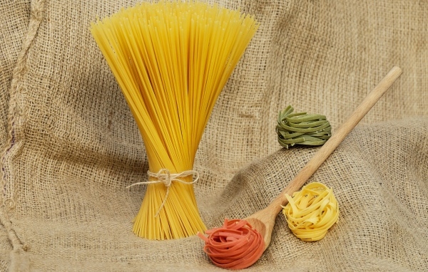 Спагетти с деревянной ложкой и макаронами на столе 