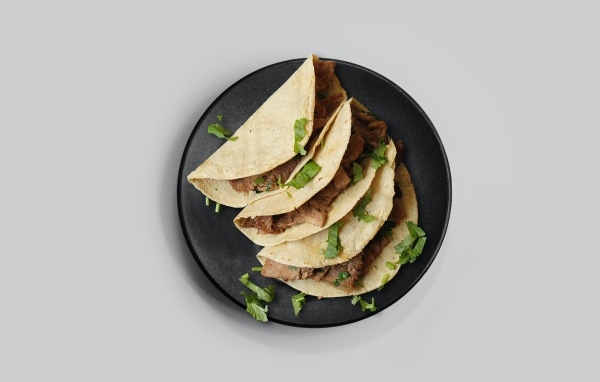 Блюдо тако в тарелке на сером фоне