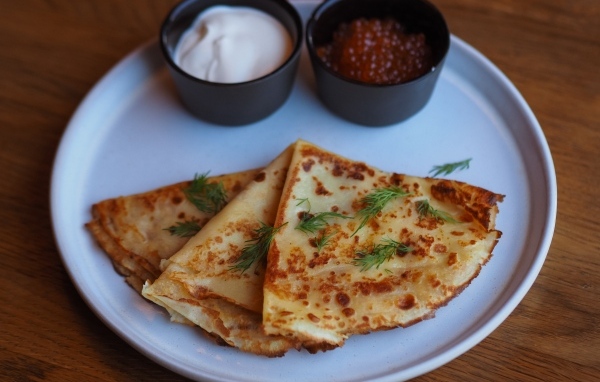 Тонкие блинчики на тарелке с красной икрой и сметаной