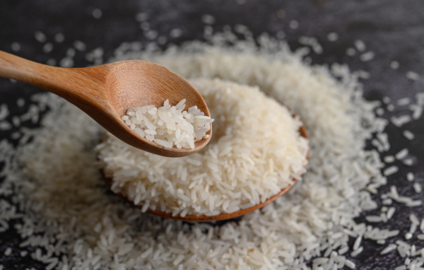 Белый рис на столе с деревянной ложкой 