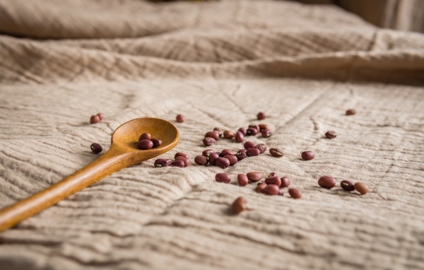 Деревянная ложка на скатерти с фасолью 